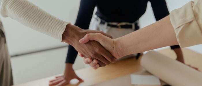 Shaking hands across desk.