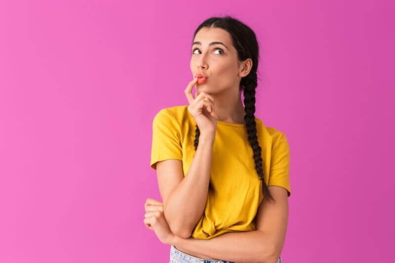 Woman thinking in front of pink background